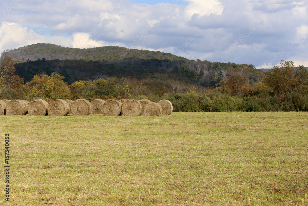 Fall hayfield in the mountains with round bales and clouds. Wide foreground. Fall hayfield in the mountains with round bales and clouds. Wide foreground.