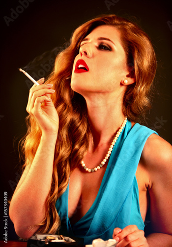 Woman smokes marijuana. Girl with proud and independent who smokes cigarette. Smoke is bad habit. Nicotinic acid is harmful to health and female beauty on black background. photo