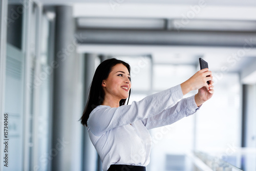 Beautiful woman at business building taking selfie photo