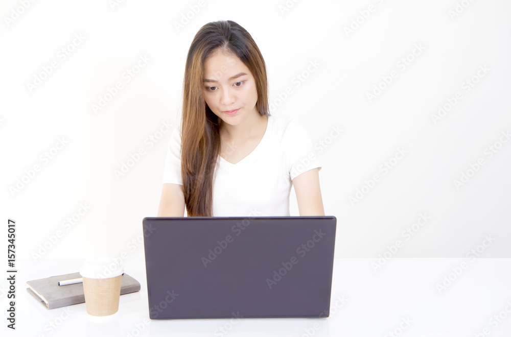 Beautiful young Asian woman sitting in front of laptop computer and looking at screen with serious face. Beautiful young Asian woman sitting in front of laptop computer and looking at screen with serious face.