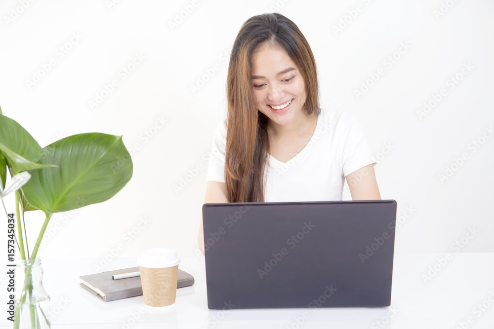Beautiful young Asian woman sitting in front of laptop computer and looking at screen with smiling face while working. Beautiful young Asian woman sitting in front of laptop computer and looking at screen with smiling face while working.