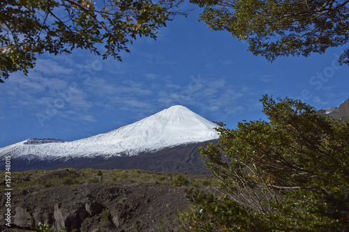 Snow capped peak of Antuco Volcano  2 979 metres  rising above a forested valley in Laguna de Laja National Park in the Bio Bio region of Chile.