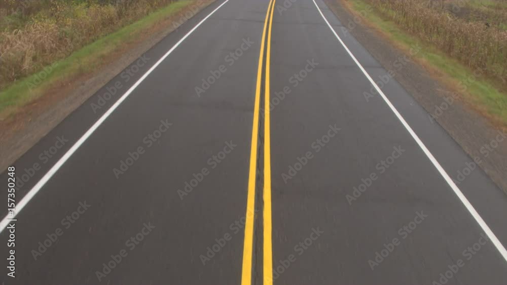 AERIAL: Flying above empty expressway leading through scenic rural autumn country. Road surface markings on empty roadway. The intersection between picturesque forest trail and interstate highway AERIAL: Flying above empty expressway leading through scenic rural autumn country. Road surface markings on empty roadway. The intersection between picturesque forest trail and interstate highway