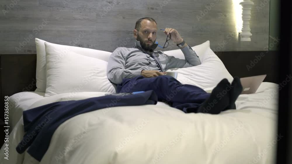 Portrait of sad, unhappy businessman lying on bed in hotel room
Portrait of sad, unhappy businessman lying on bed in hotel room