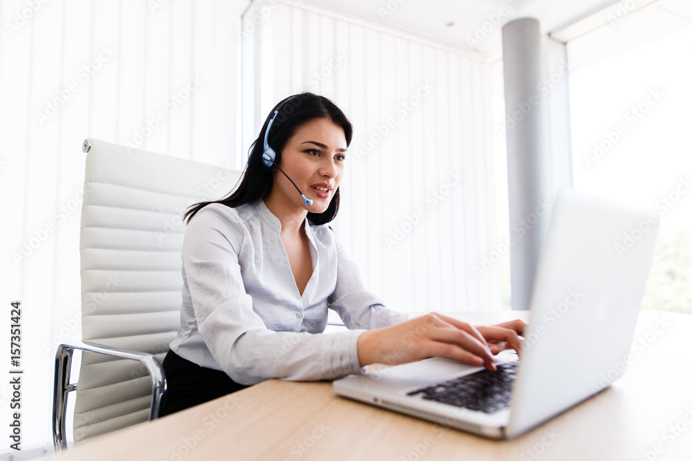 Attractive woman talking with customer at her work desk with headset Attractive woman talking with customer at her work desk with headset