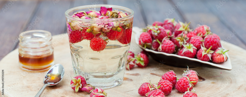 Naklejka premium Herbal tea with rose buds and fresh raspberry.