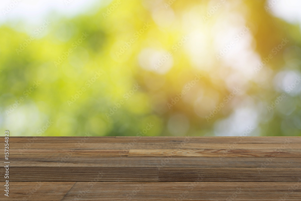 Wood table and blurry green sunlight in background. Wood table and blurry green sunlight in background.