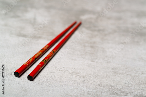 Red chopsticks on concrete background with selective focus
