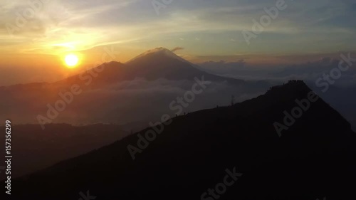 Drone footage of spectacular sunset in mountains with silhouettes of people walking on top photo