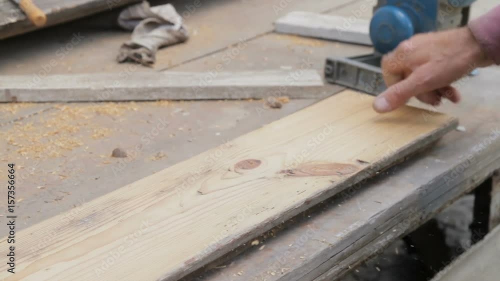 Hands of carpenter planing a beam with electric wood planer tool. Antique furniture restoration services close-up Hands of carpenter planing a beam with electric wood planer tool. Antique furniture restoration services close-up