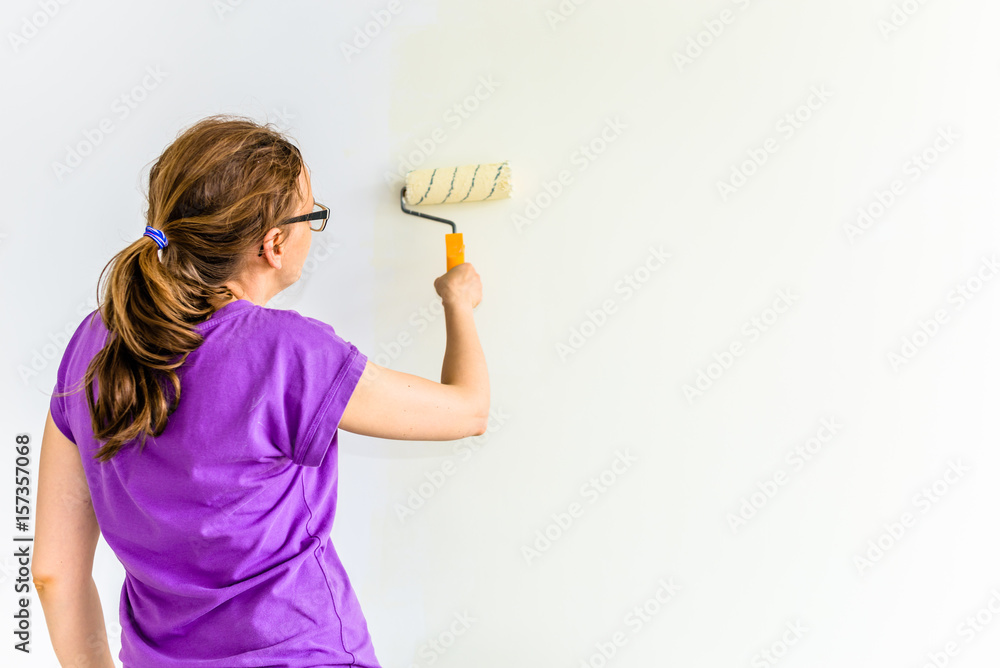 Painting wall using paint brush, working indoors, home renovation concept Painting wall using paint brush, working indoors, home renovation concept