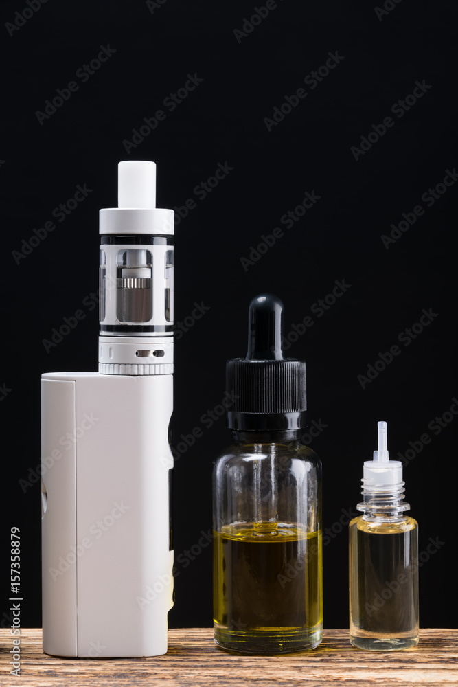 Electronic cigarette and aromas in bottles on a black background