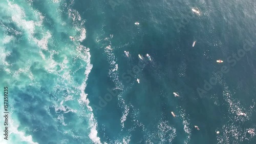 Top view drone shot of surfers paddling in crystal blue ocean water photo