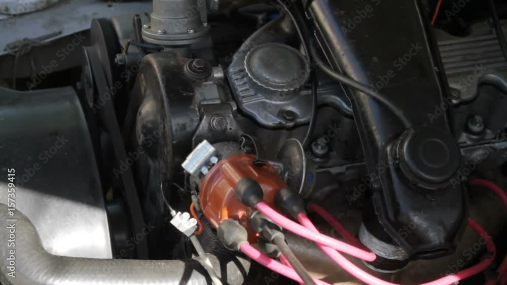 Old mechanic repairing an old car. Under the hood of the car checks the work of carb and engine Old mechanic repairing an old car. Under the hood of the car checks the work of carb and engine