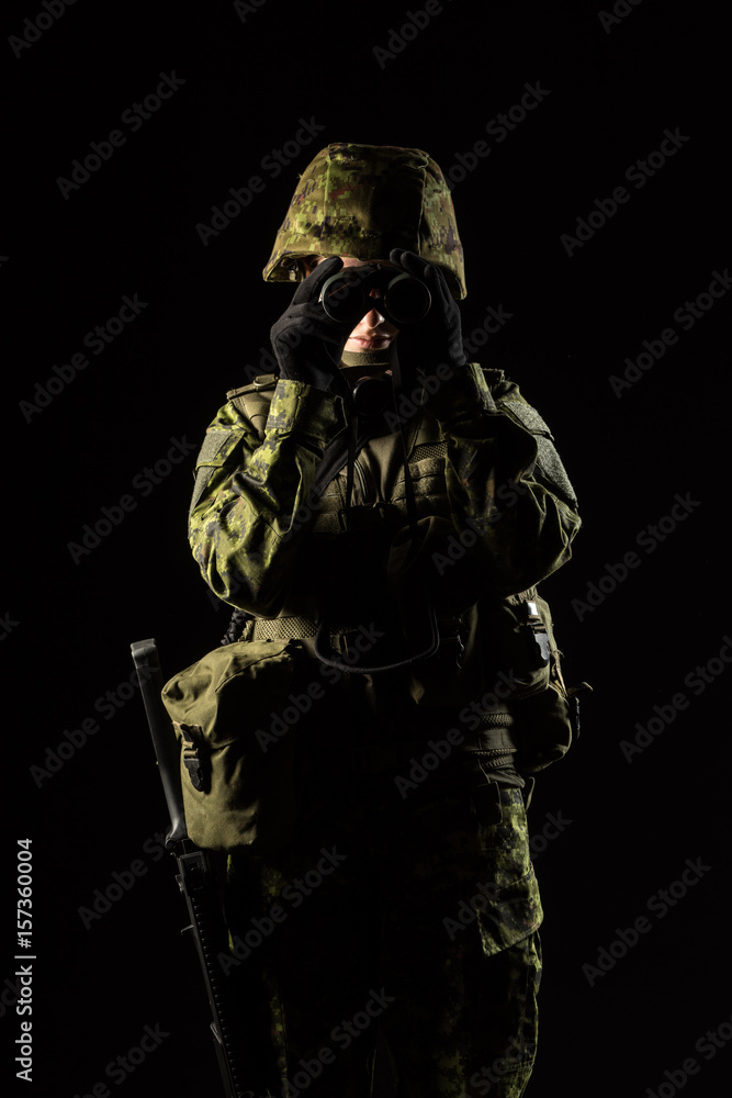 Portrait of armed woman with camouflage. Young female soldier observe with binoculars. Child soldier with gun in war, black background. Military, army people concept Portrait of armed woman with camouflage. Young female soldier observe with binoculars. Child soldier with gun in war, black background. Military, army people concept