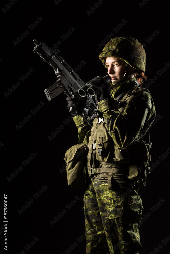 Portrait of armed woman with camouflage. Young female soldier observe with binoculars. Child soldier with gun in war, black background. Military, army people concept Portrait of armed woman with camouflage. Young female soldier observe with binoculars. Child soldier with gun in war, black background. Military, army people concept