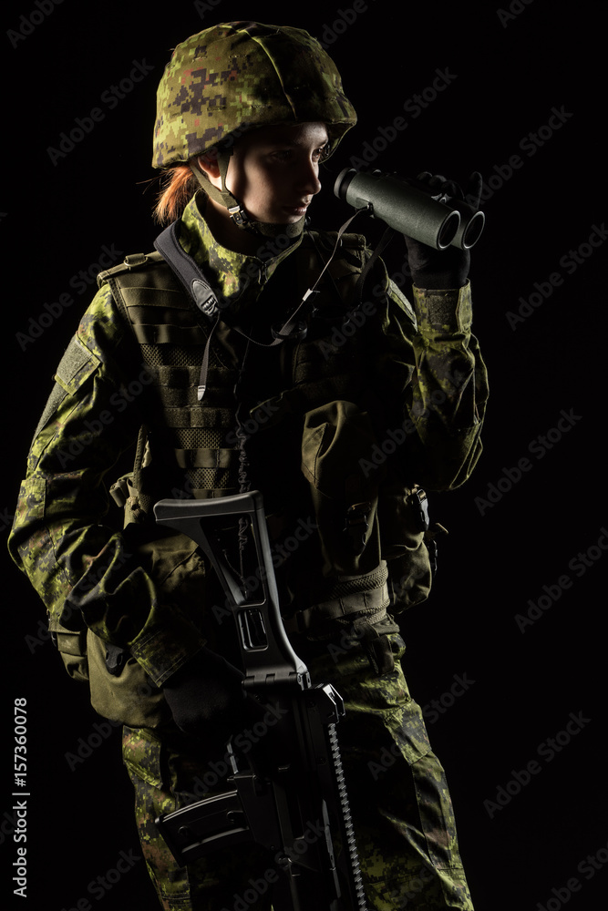 Portrait of armed woman with camouflage. Young female soldier observe with binoculars. Child soldier with gun in war, hause ruins background.  Military, army people concept