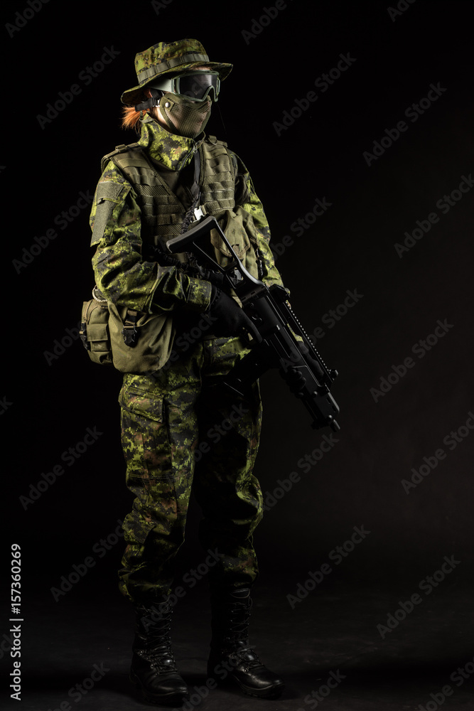 Portrait of armed woman with camouflage. Young female airsoft sniper observe with firearm. Soldier with gun in war, black background. Military, army people concept Portrait of armed woman with camouflage. Young female airsoft sniper observe with firearm. Soldier with gun in war, black background. Military, army people concept