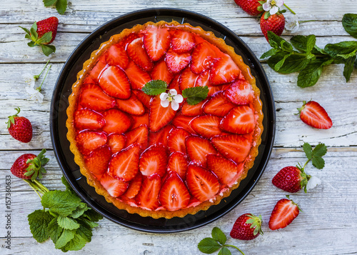 Delicious sponge cake with jelly and fresh strawberries on a wooden background.