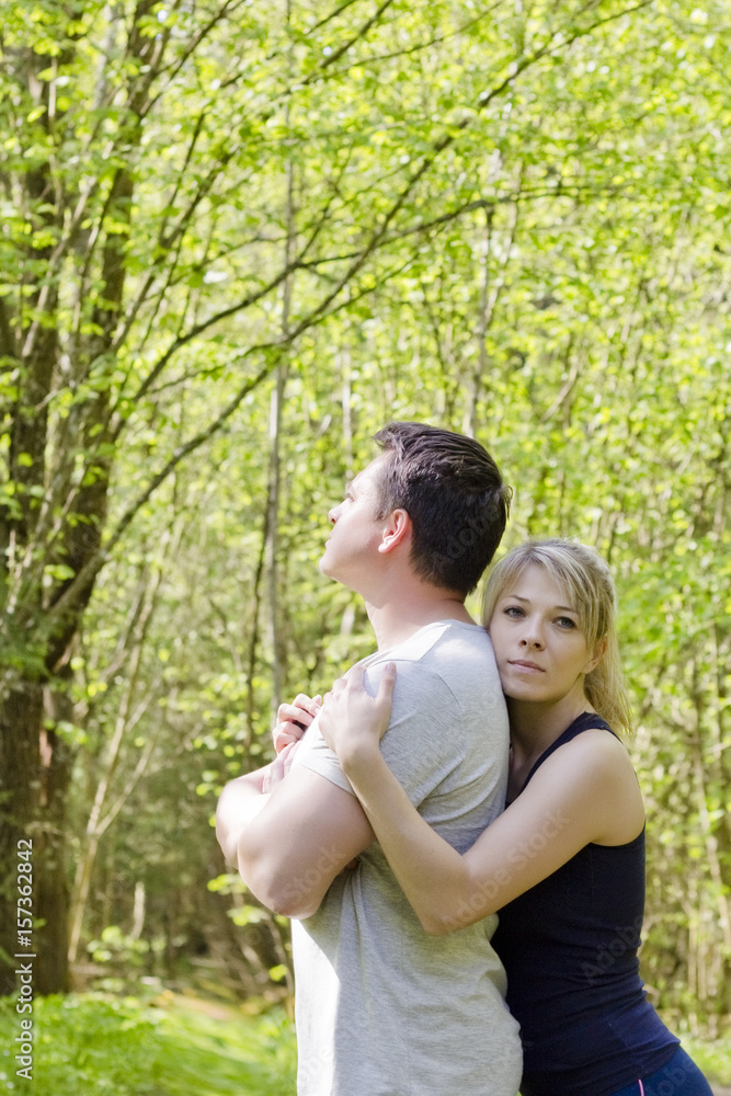Woman hugs a man who is standing with her back to her. The concept of family problems, forgiveness Woman hugs a man who is standing with her back to her. The concept of family problems, forgiveness