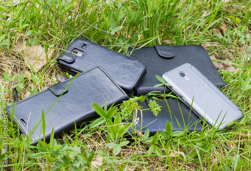 Several smartphones in different cover among grass
