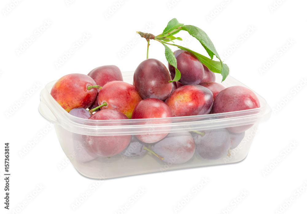 Plums with twig and leaves in the plastic container Plums with twig and leaves in the plastic container
