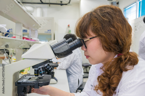 Female scientist looking in microscope in laboratory Laboratory