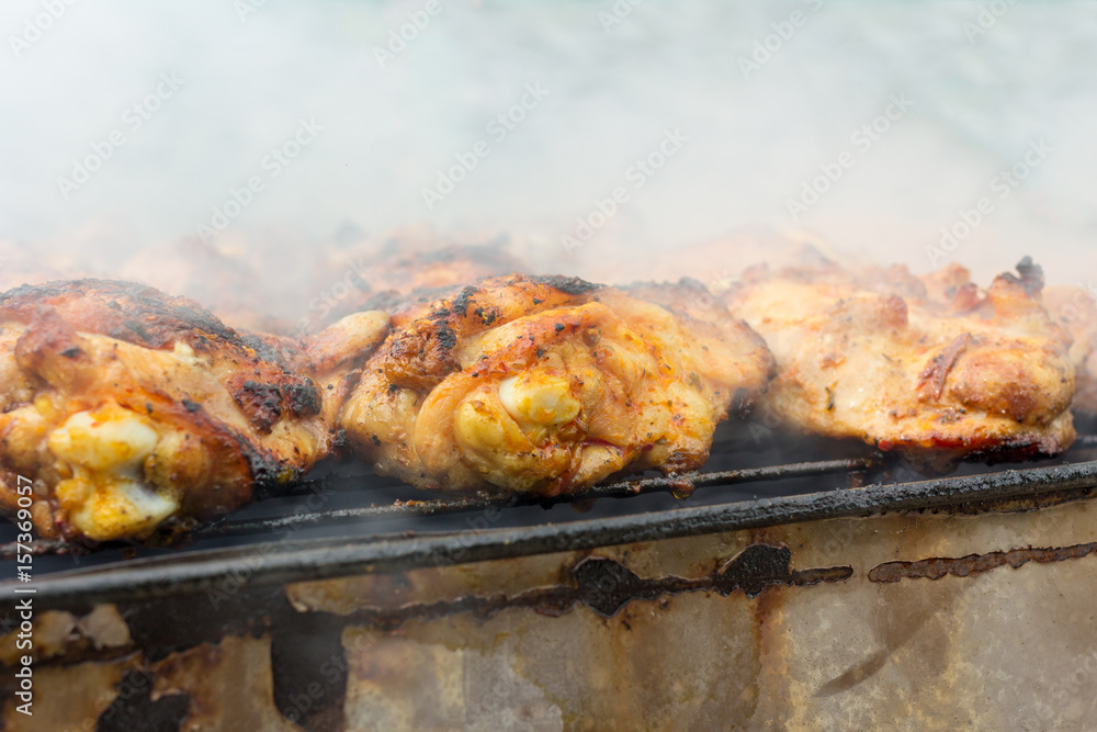 Chicken kebab prepared in a rusty brazier. In the background smoke. Chicken kebab prepared in a rusty brazier. In the background smoke.