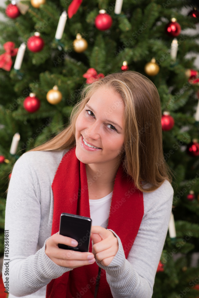 Blondes Mädchen schreibt sms vor einem weihnachtsbaum Blondes Mädchen schreibt sms vor einem weihnachtsbaum