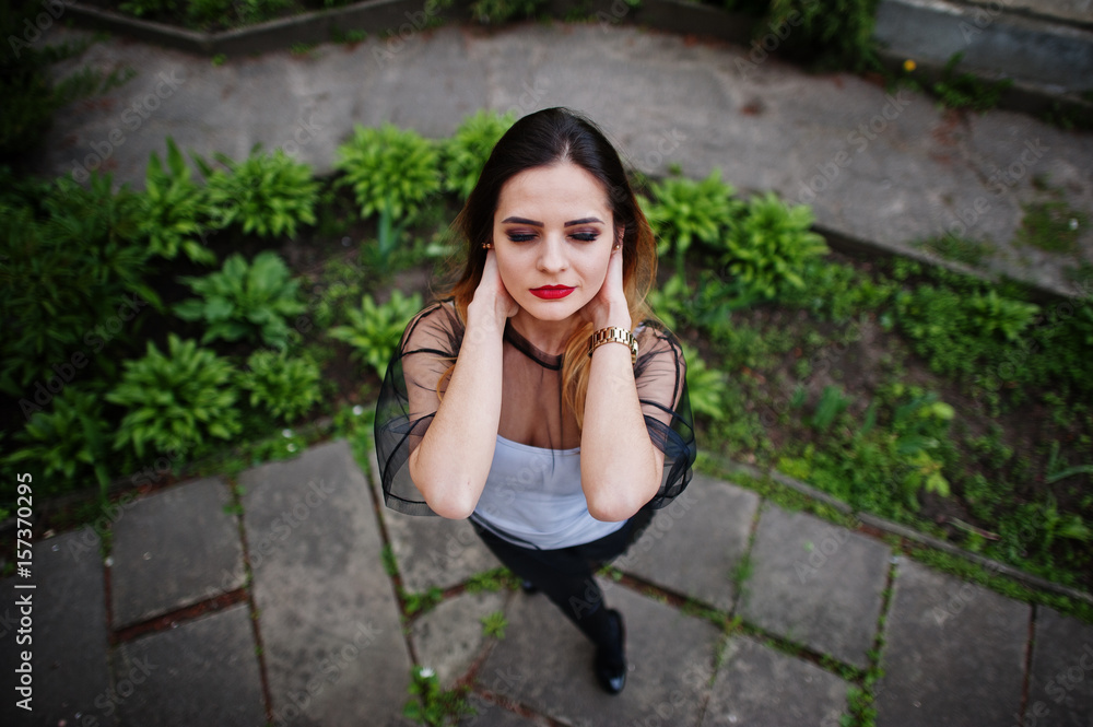 Above view of fashionable woman look at white shirt, black transparent clothes, leather pants, posing at street. Concept of fashion girl. Above view of fashionable woman look at white shirt, black transparent clothes, leather pants, posing at street. Concept of fashion girl.