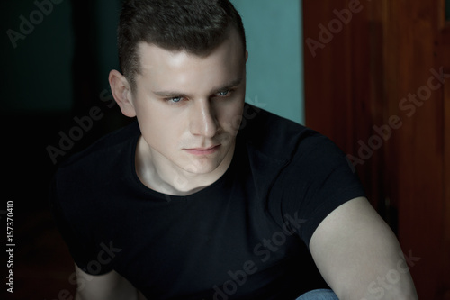Headshot studio portrait of young man in low-key lighting