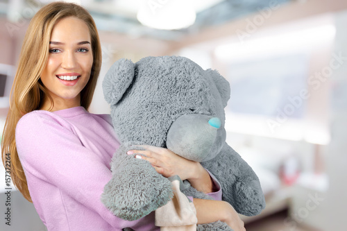 Photos Casual smiling young woman holding teddy bear