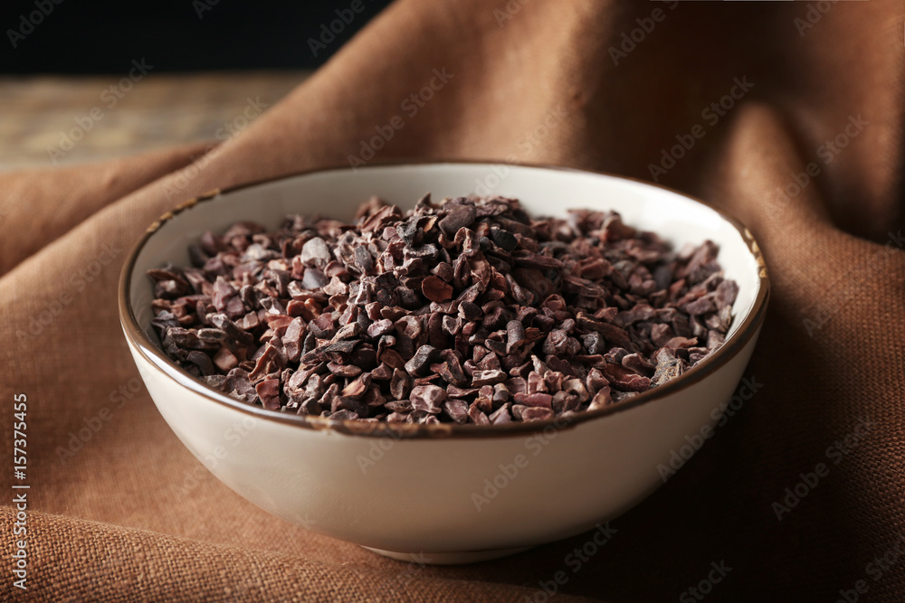 Bowl with cocoa nibs on brown cloth background Bowl with cocoa nibs on brown cloth background