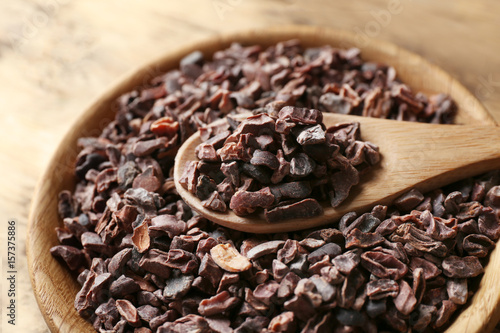 Wooden bowl and spoon with cocoa nibs, closeup
