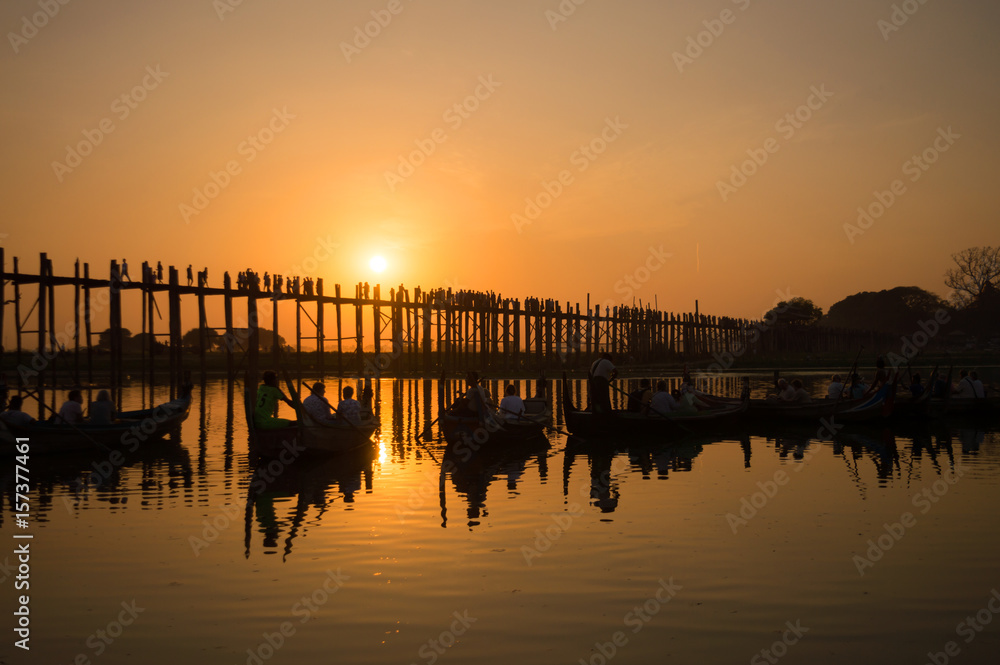 Silhouettes of tourists in boats admiring U Bein bridge over the Taungthaman Lake at sunset, in Amarapura, Mandalay, Myanmar