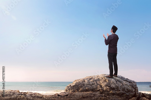 Religious asian muslim man raising hand and praying