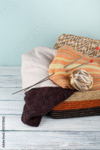 Fototapeta Naklejka Na Ścianę i Meble -  Ball of wool, needles and woolen sweater with spokes for handmade knitting in basket on wooden table.
