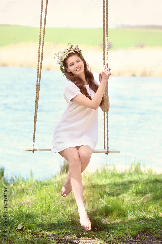 Beautiful young woman on swing near river Beautiful young woman on swing near river