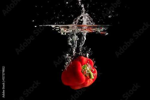 Tableau sur toile Red pepper splashing water on black background