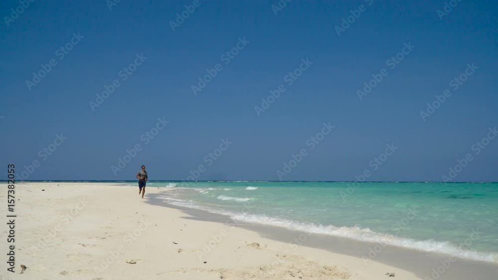 Man running along beach. Fitness sports runner man jogging on beach. Handsome young fit sporty male athlete running outside on beautiful beach training. 4K video. Man running along beach. Fitness sports runner man jogging on beach. Handsome young fit sporty male athlete running outside on beautiful beach training. 4K video.