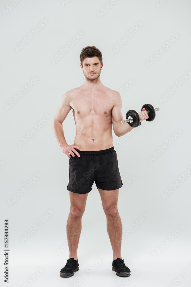Portrait of a handsome fit sportsman standing and holding dumbbell Portrait of a handsome fit sportsman standing and holding dumbbell