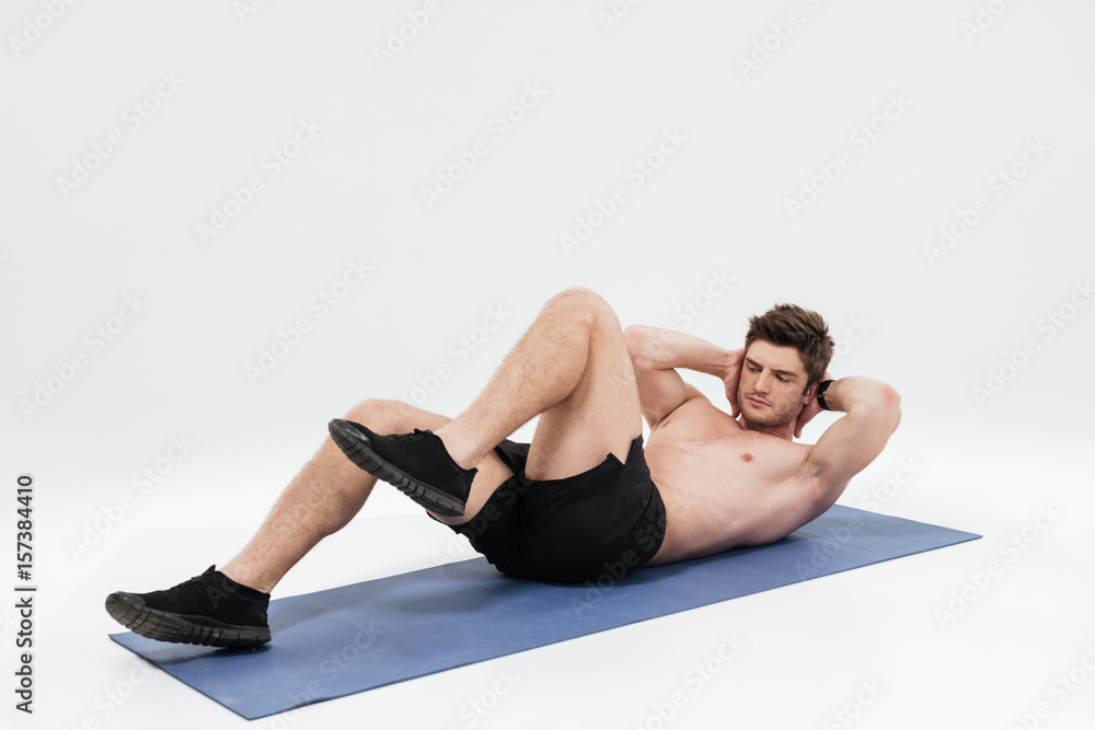 Young handsome sportsman doing leg exercises on a fitness mat Young handsome sportsman doing leg exercises on a fitness mat