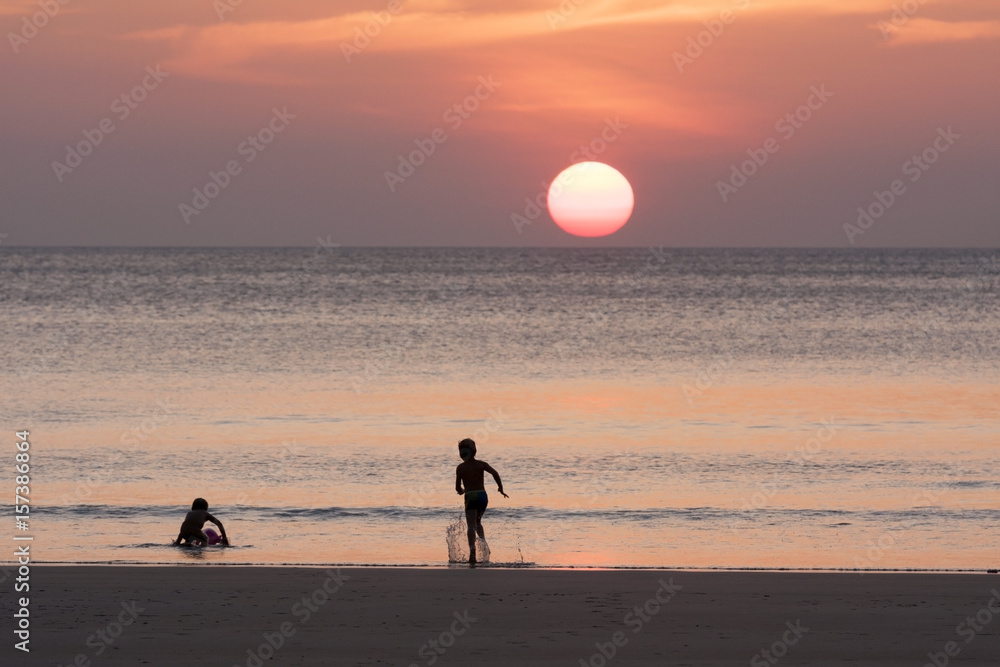 Boys enjoying beautiful sunset on the beach for holiday time, silhouette sunset at   the sea, selective focus