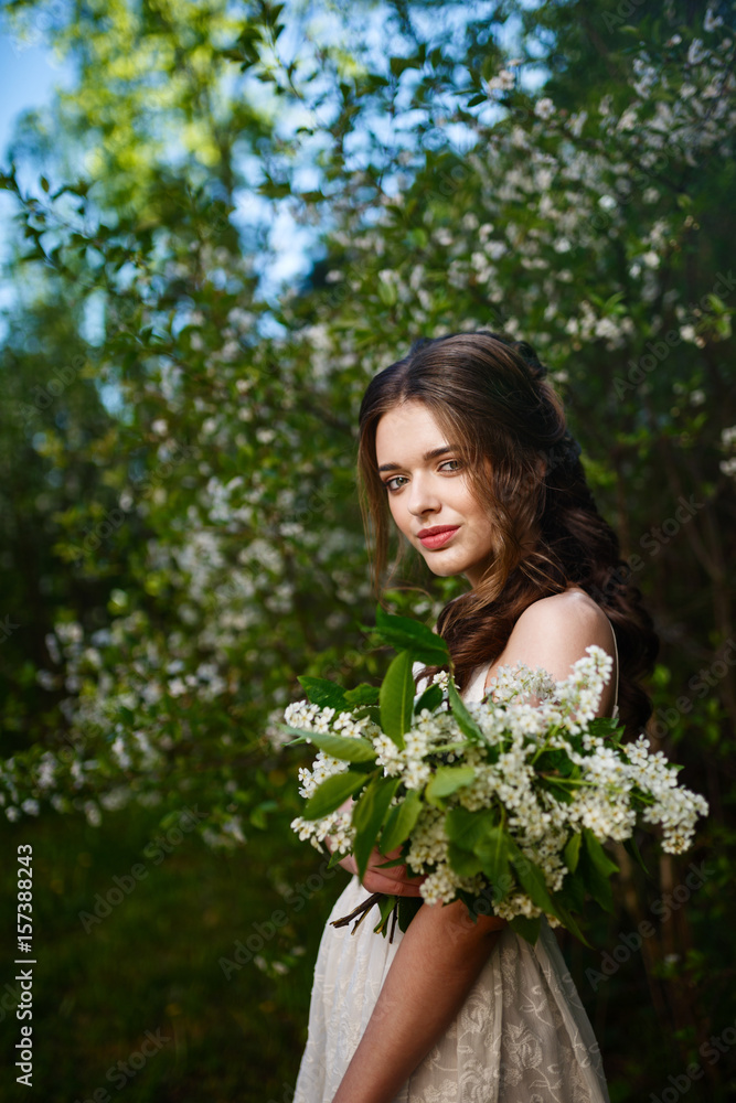 Portrait beautiful happy woman enjoying smell in a flowering spring blooming garden. Bright and fashionable smiling girl near blossom cherry tree with white flowers in spring garden. Landscape. Spring Portrait beautiful happy woman enjoying smell in a flowering spring blooming garden. Bright and fashionable smiling girl near blossom cherry tree with white flowers in spring garden. Landscape. Spring