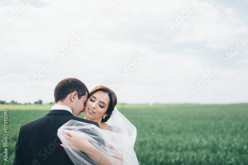 The beautiful couple in love embracing and standing on the field