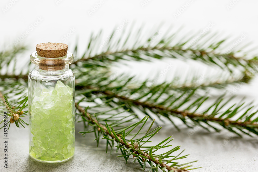 Bottles of sea salt and fir branches for aromatherapy and spa on white table background Bottles of sea salt and fir branches for aromatherapy and spa on white table background