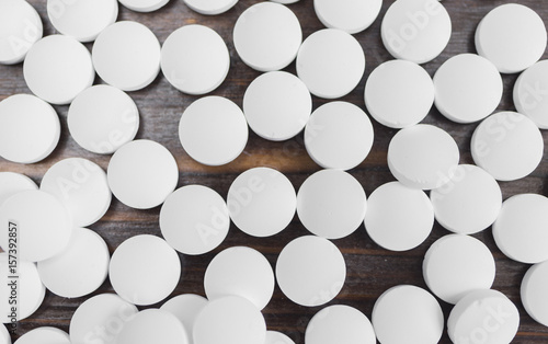 Many white tablets on a wooden background