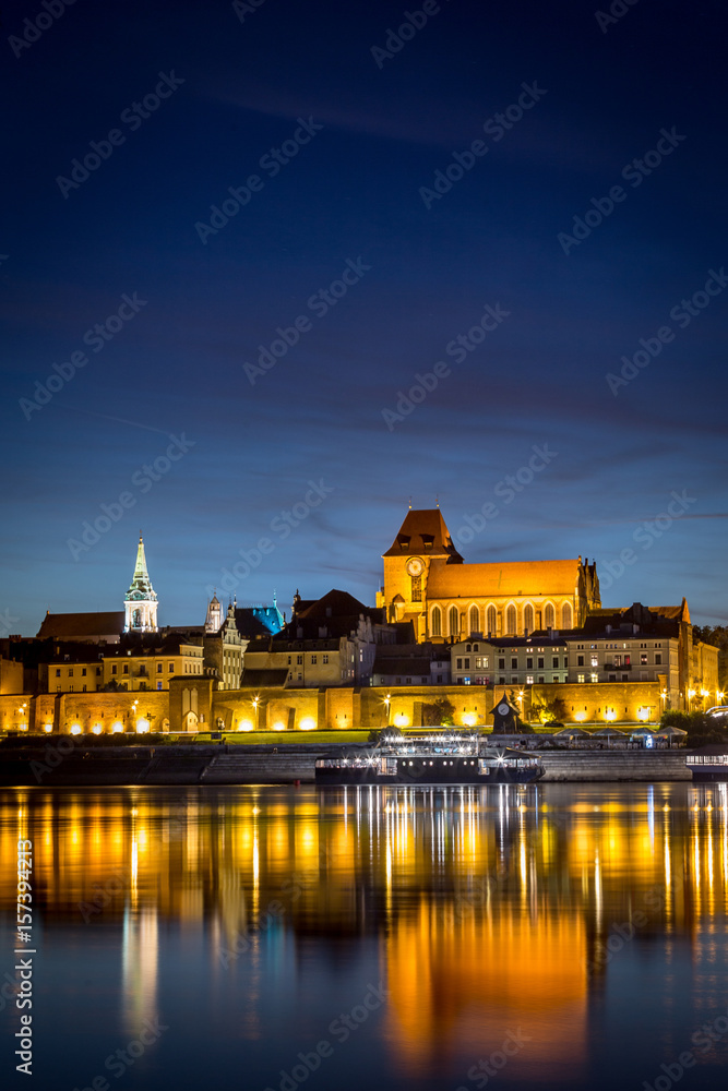 Fototapeta premium Torun's Old Town panorama with its reflection in Vistula river at the evening