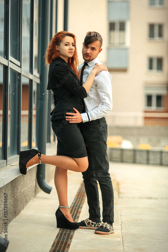 Couple in love. Handsome guy and pretty girl posing opposite modern urban background.