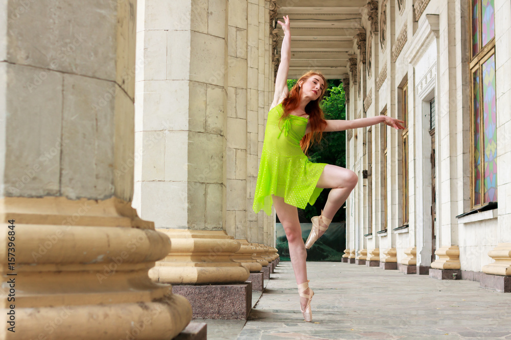 Ballerina dance in a green dress on a background of white columns. ballet dancer posing